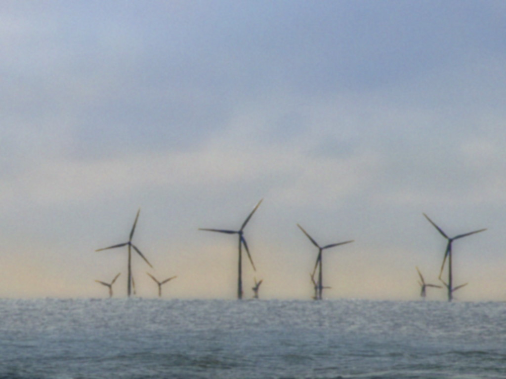 Ein gutes dutzend Windräder im Merr am Horizont in tiefstehender Sonne.