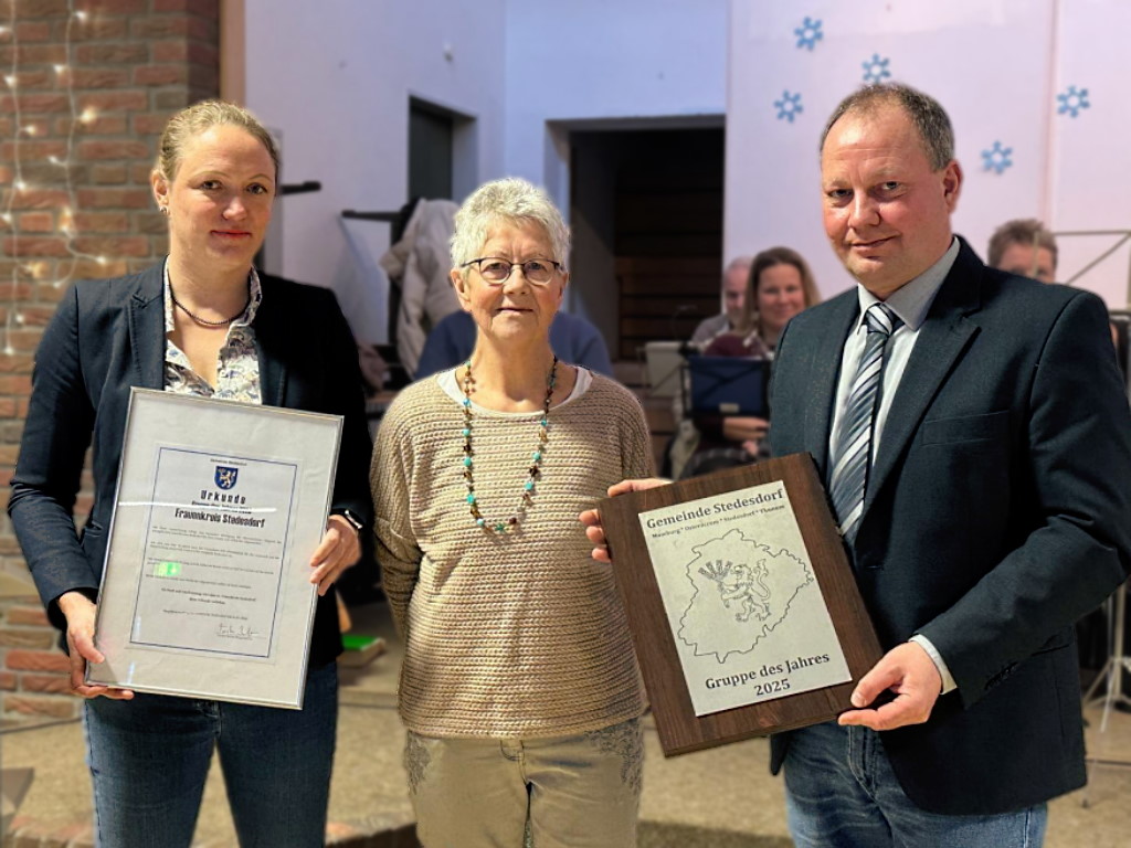 Bild mit drei Personen welche zwei Urkunden presentieren im Hintergrund Mitglieder des Posaunenchors